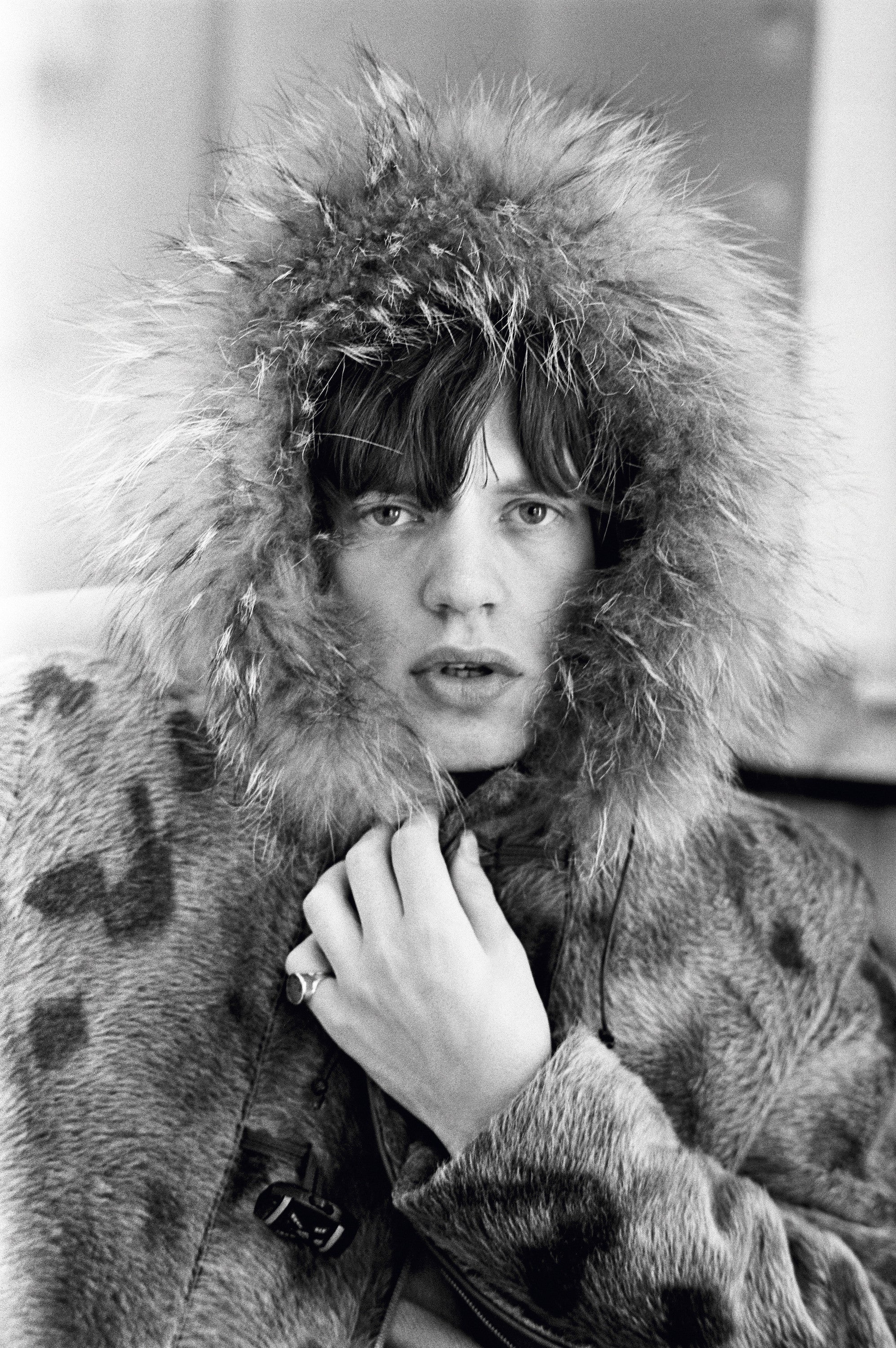 Rolling Stones singer Mick Jagger posing in a fur parka, with a fur trimmed hood, 1964.