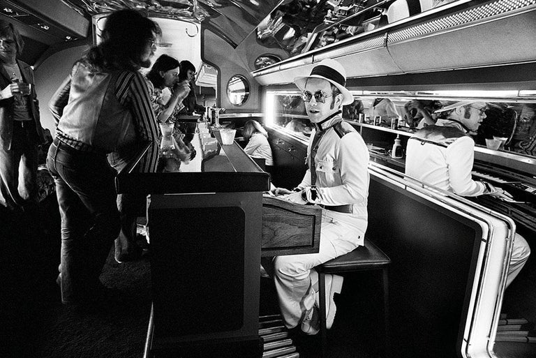 English singer and songwriter Elton John sitting at piano on Starship airplane.
