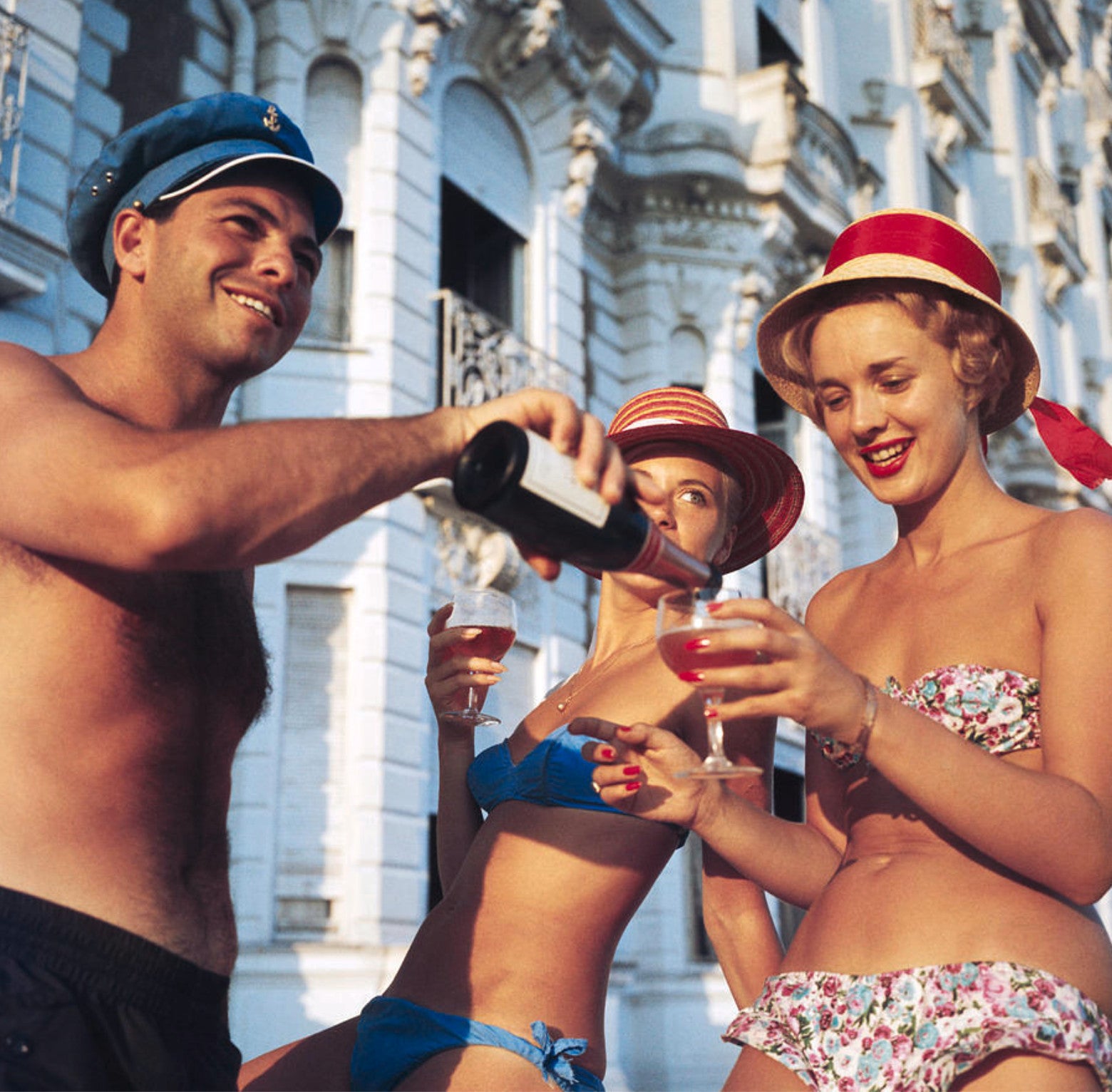 1958: Swimsuited revellers enjoy a glass of wine outside the Carlton Hotel, Cannes.