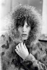 Rolling Stones singer Mick Jagger posing in a fur parka, with a fur trimmed hood, 1964.