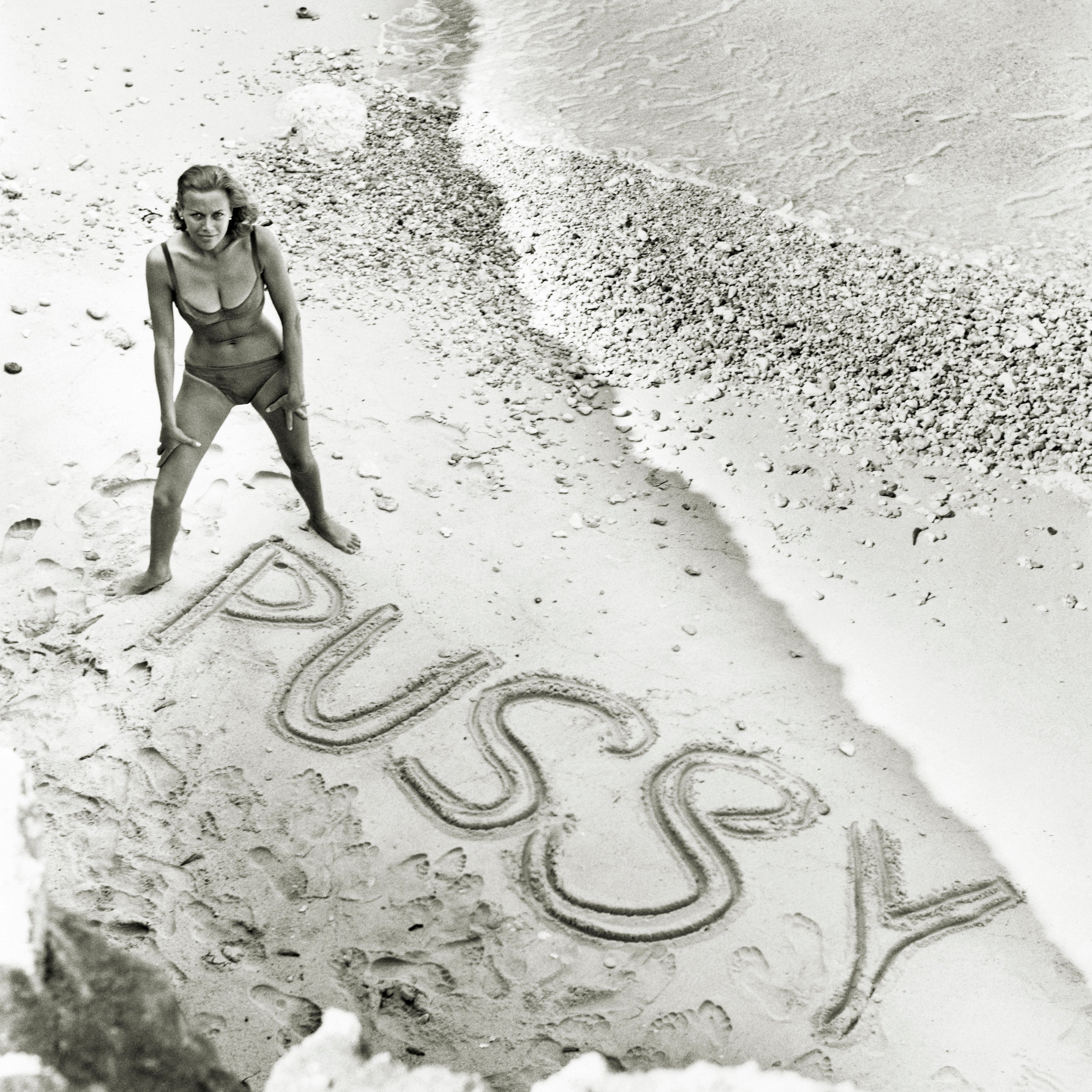 English actress Honor Blackman on a beach for a publicity shot for the 1964 James Bond ‘Goldfinger’. Spelt out in the sand is the name of her character, Pussy Galore.
