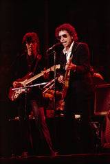 Bob Dylan performs with Robbie Robertson on stage.